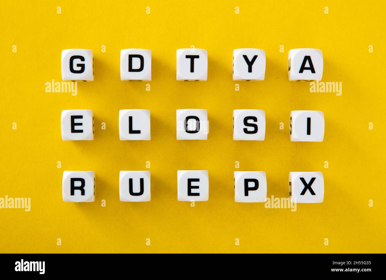 White cubes with letters scattered randomly on a yellow background Stock Photo