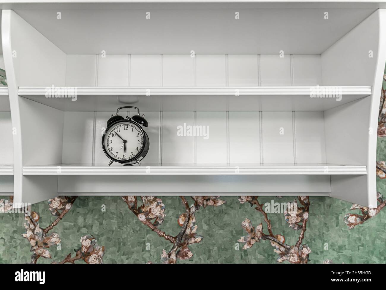 Classic vintage alarm clock on the shelf in the interior of the room