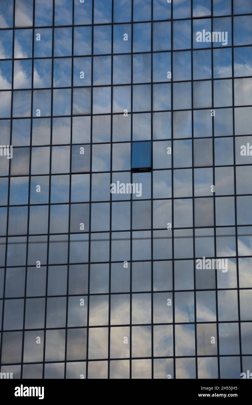 One open window in a glass building reflecting sky and clouds Stock Photo