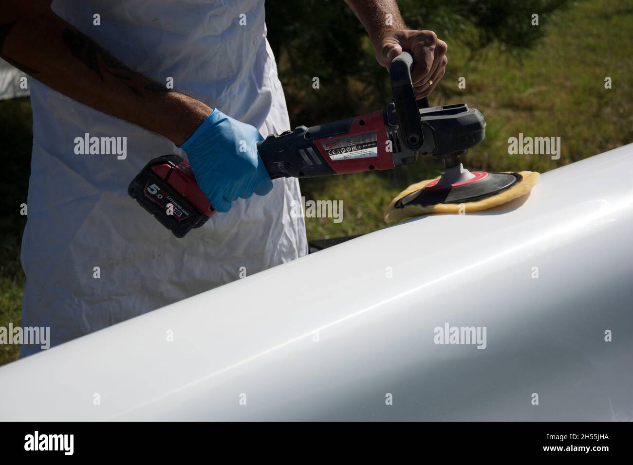 Man at work polishing a white surface with electric tool Stock Photo