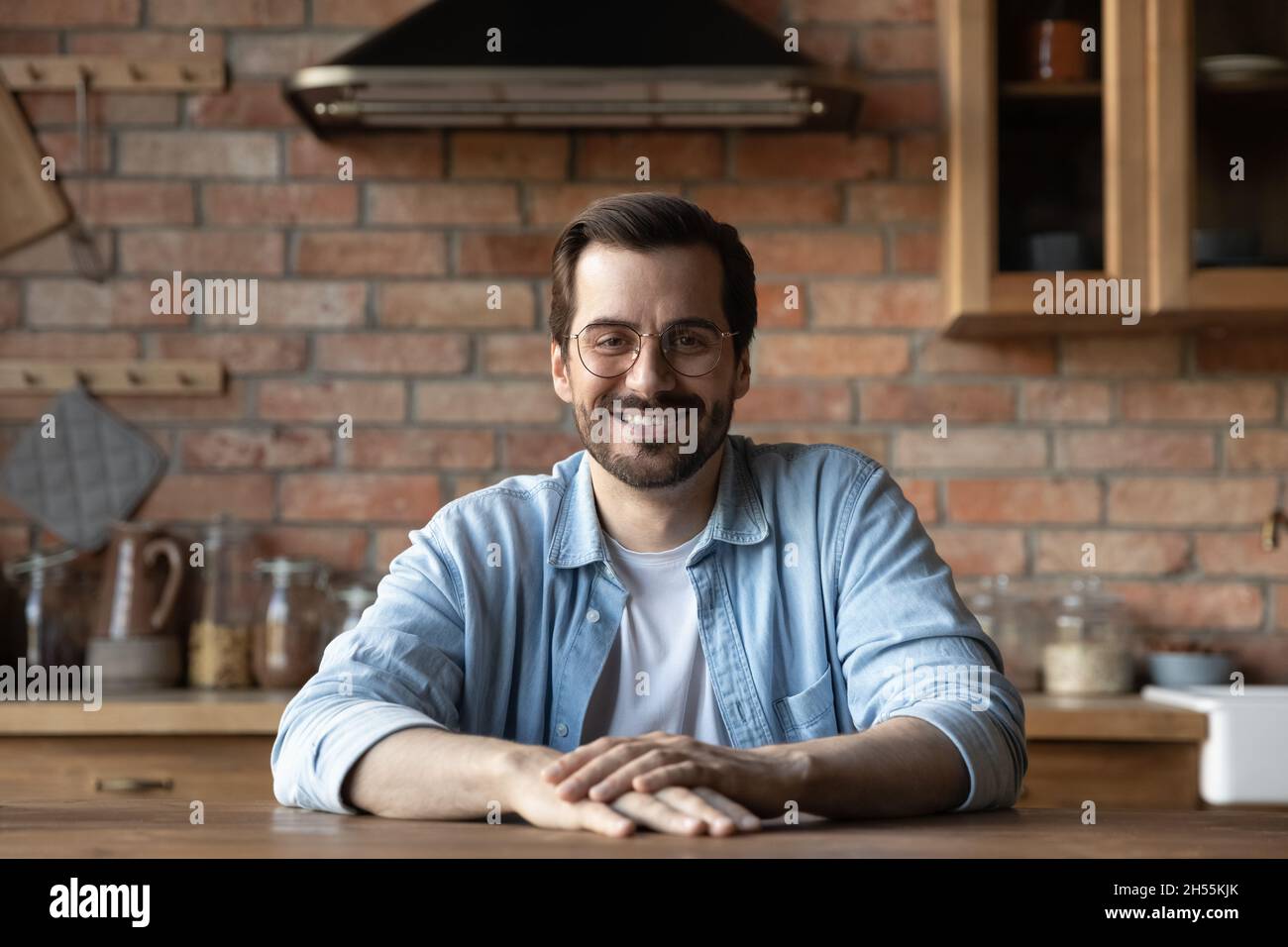 Portrait of happy young man sit at table in kitchen Stock Photo