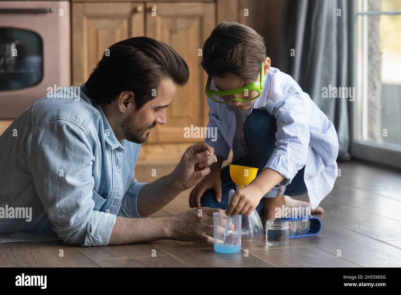 Caring millennial father and preteen son doing funny chemical experiments Stock Photo