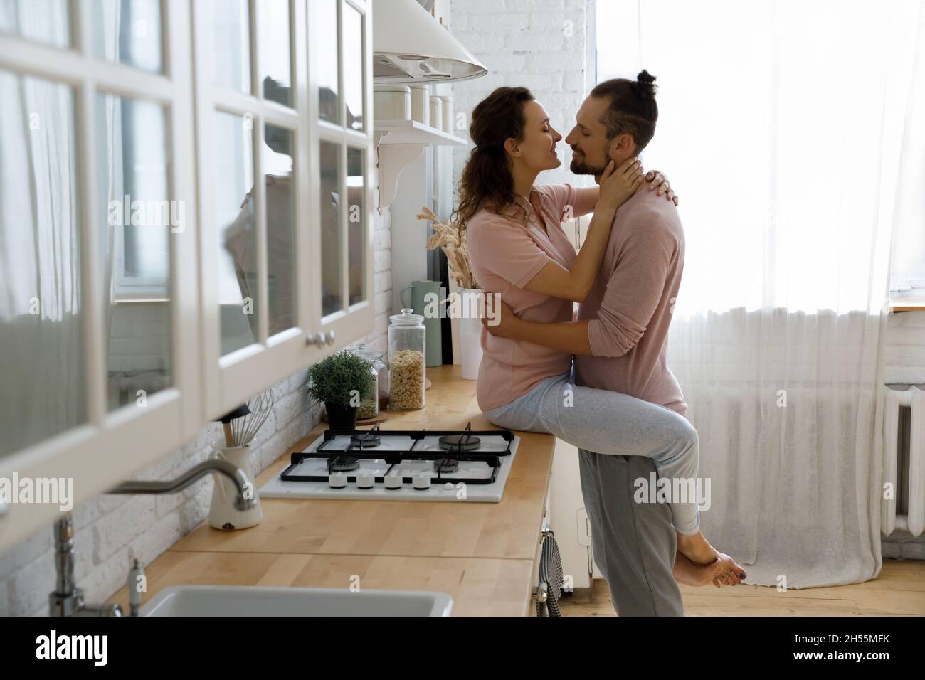 Happy young wife kissing affectionate husband at home. Stock Photo