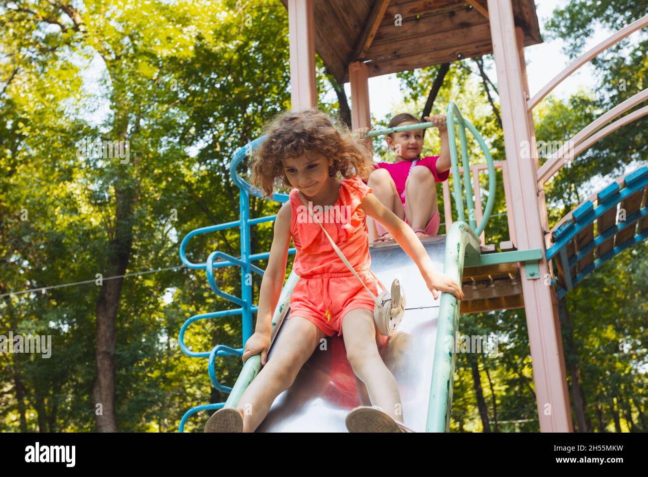 The little girl is sitting on a slide in the playground Stock Photo - Alamy