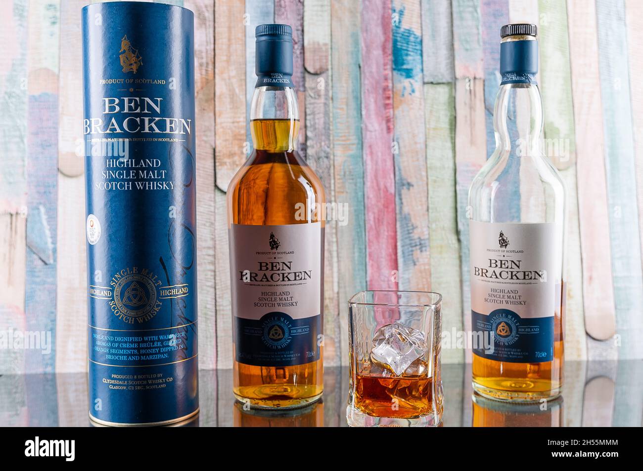 two bottles of Ben Bracken Single malt whiskey with a glass and ice cubes in front of a colorful wooden background Stock Photo