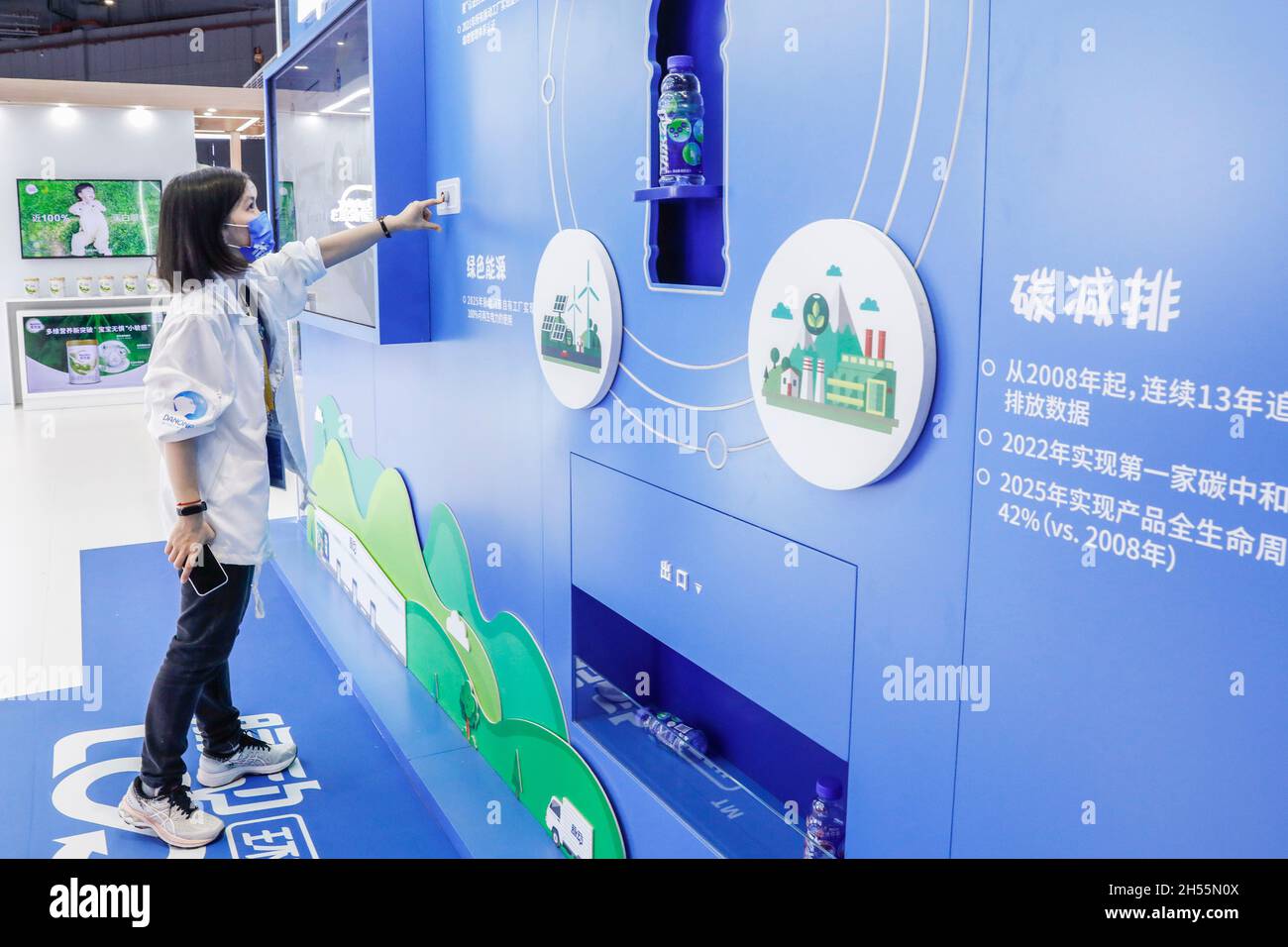 Shanghai. 6th Nov, 2021. A staff member demonstrates how to use an intelligent plastic bottle recycling machine at the Food and Agricultural Products Exhibition Area of the 4th China International Import Expo (CIIE) in east China's Shanghai, Nov. 6, 2021. The intelligent plastic bottle recycling machine at Danone booth can recycle plastic bottles thrown away by visitors and turns them into soft fabrics. Fabrics made from 16 bottles can make a coat. Credit: Zhang Yuwei/Xinhua/Alamy Live News Stock Photo