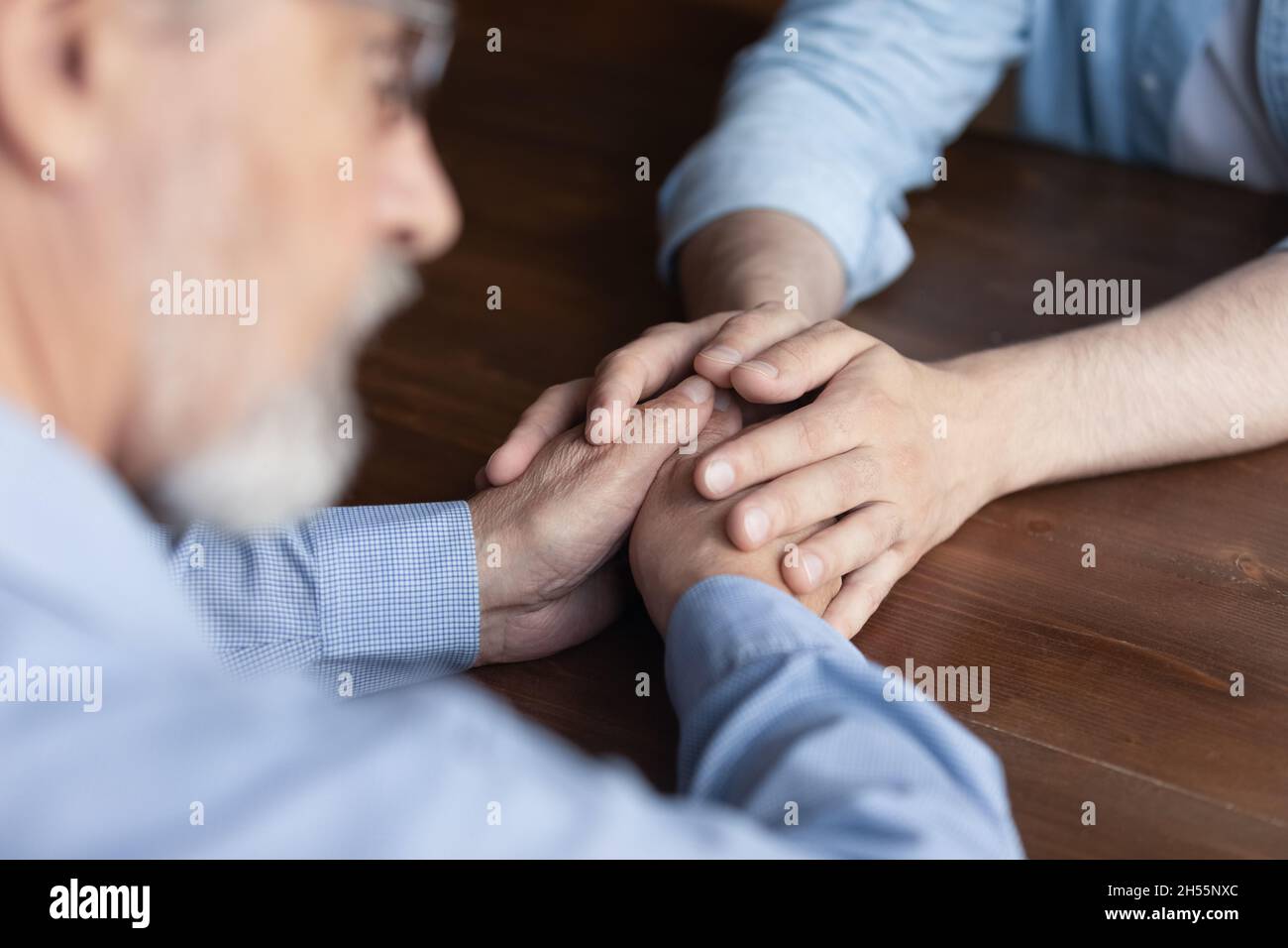 Caring young man adult child hold old man parent hands Stock Photo