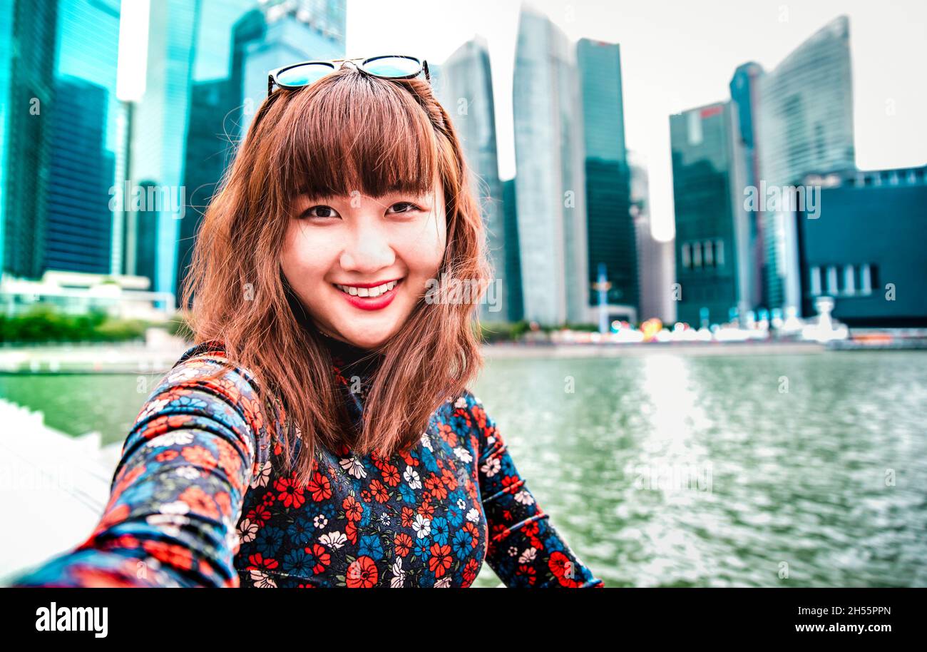 Young asian woman taking happy selfie traveling at Singapore skyline - Wanderlust life style concept with millenial girl having fun Stock Photo