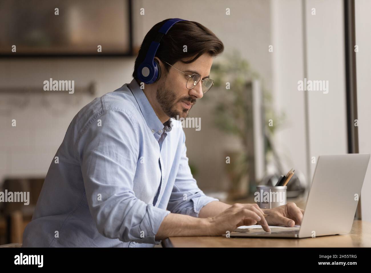 Focused young 30s businessman in headphones using computer. Stock Photo