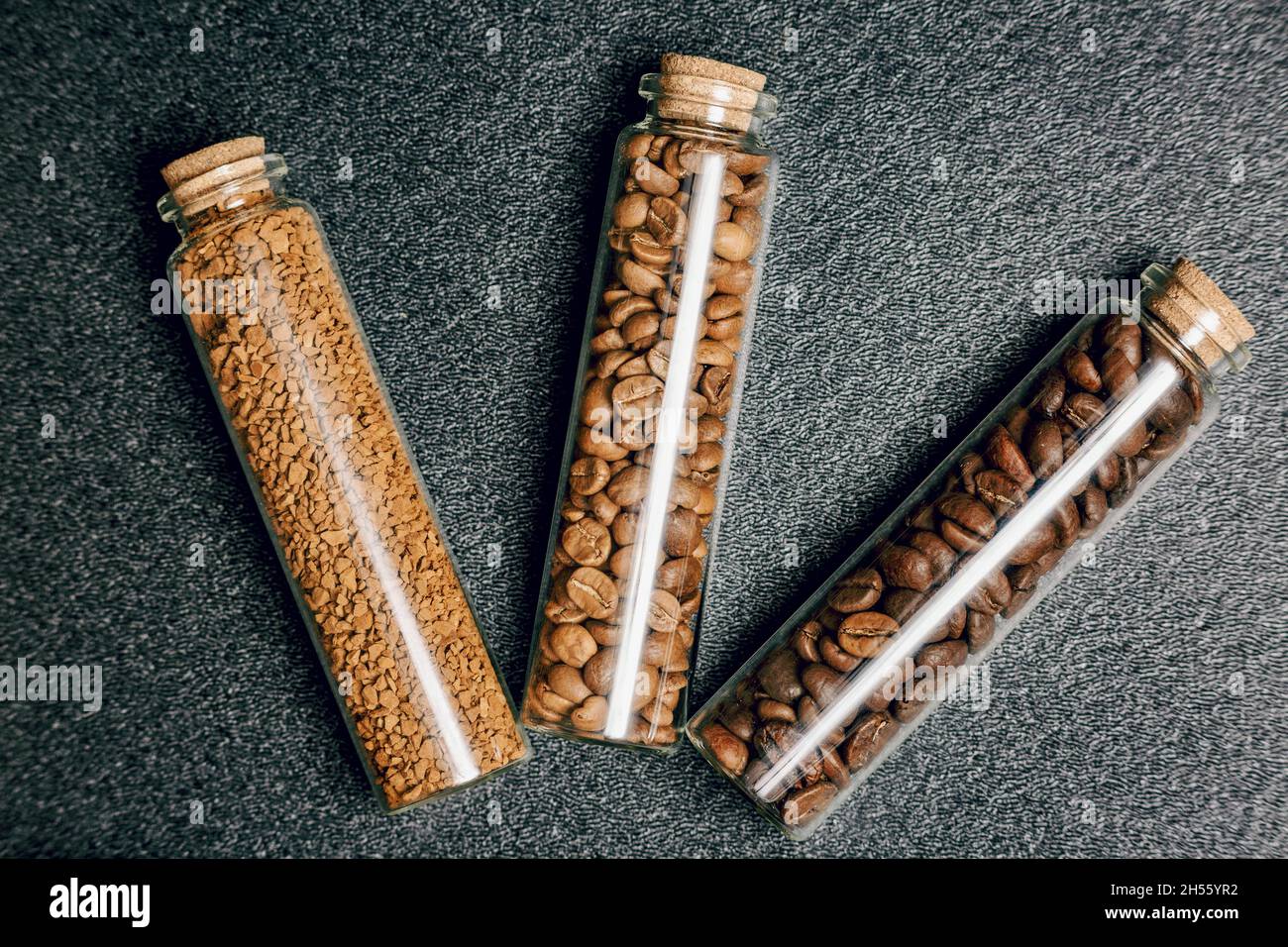 Top view of different types of coffee beans in three mini glass bottles Stock Photo
