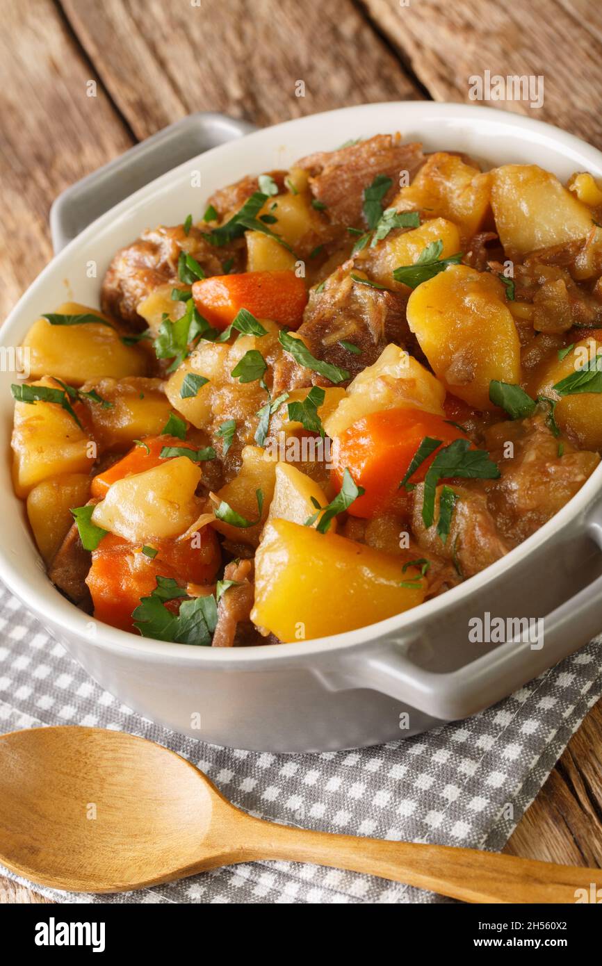 Stovies is a popular Scottish dish made of potatoes, onions, carrot and traditionally leftover roast meat close up in the bowl on the table. Vertical Stock Photo