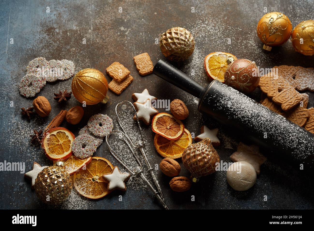 Cookies, Christmas tree balls, baking tools, dry oranges, and nuts on the table Stock Photo