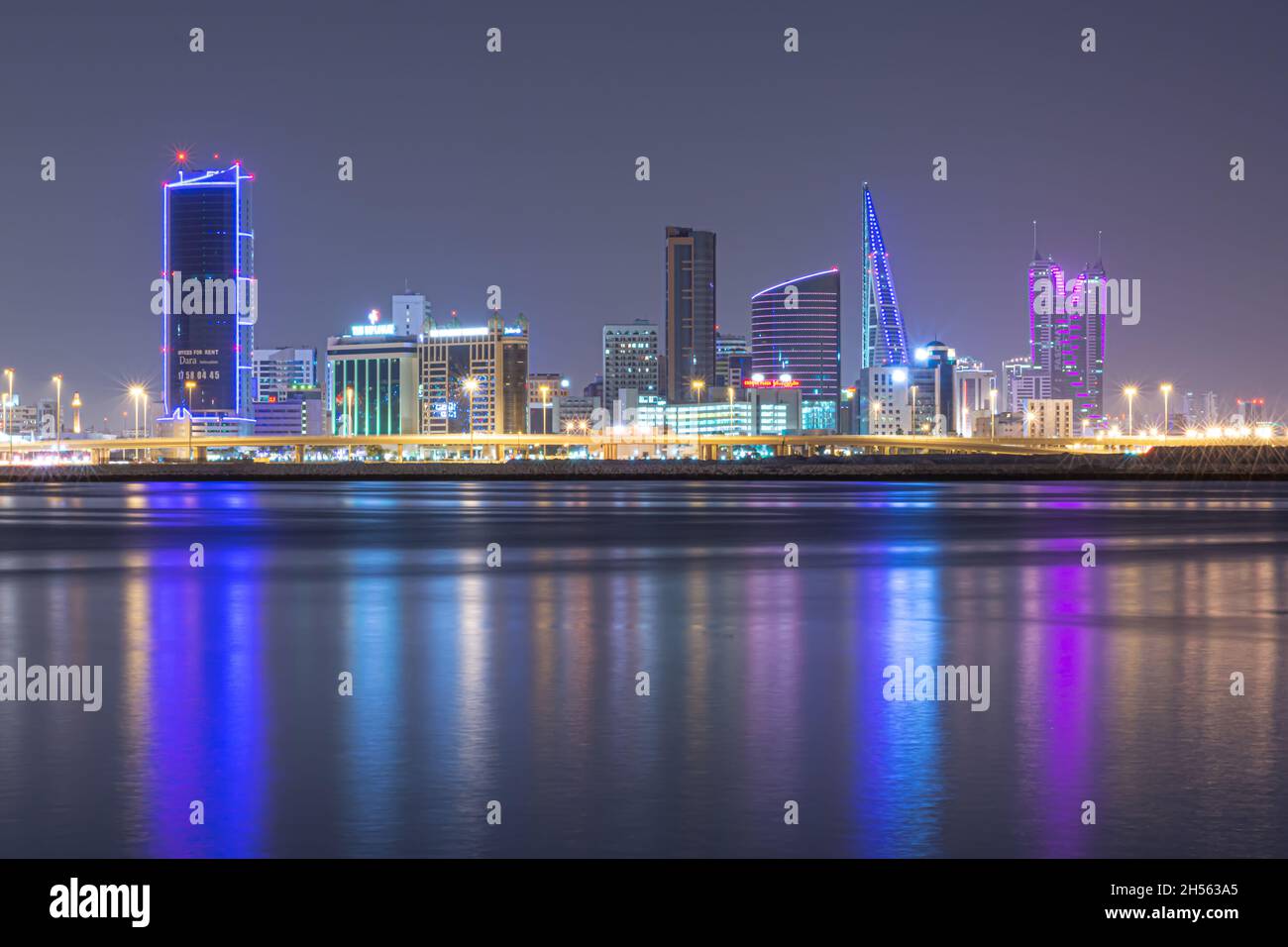 Night modern city skyline with neon lights and reflection in the water. Manama, the Capital of Bahrain, Middle East Stock Photo