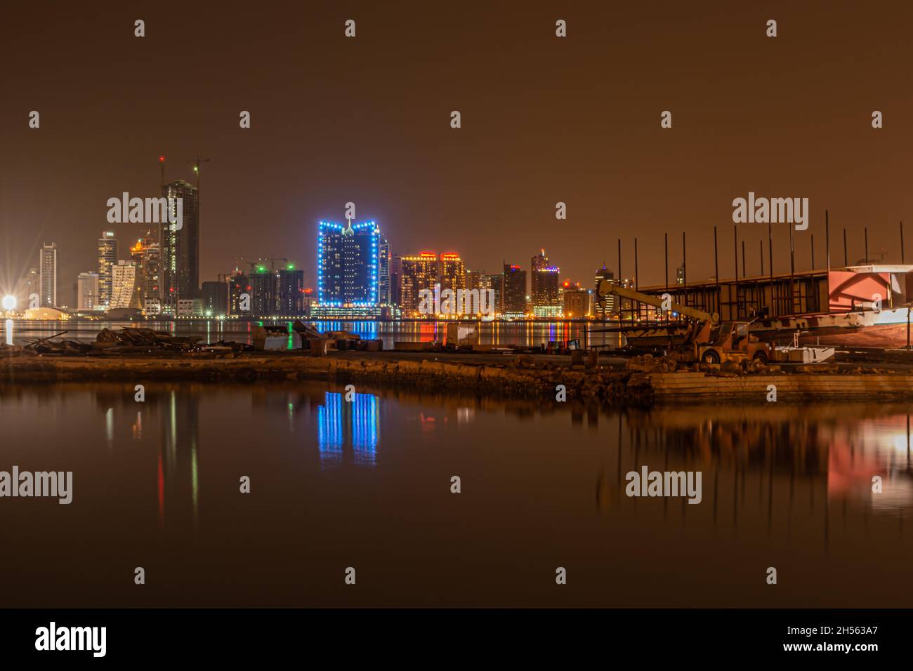 Night modern city skyline with neon lights and reflection in the water. Manama, the Capital of Bahrain, Middle East Stock Photo