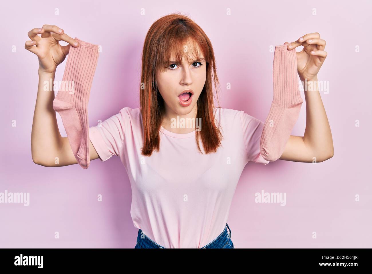 Redhead young woman holding socks in shock face, looking skeptical and  sarcastic, surprised with open mouth Stock Photo - Alamy