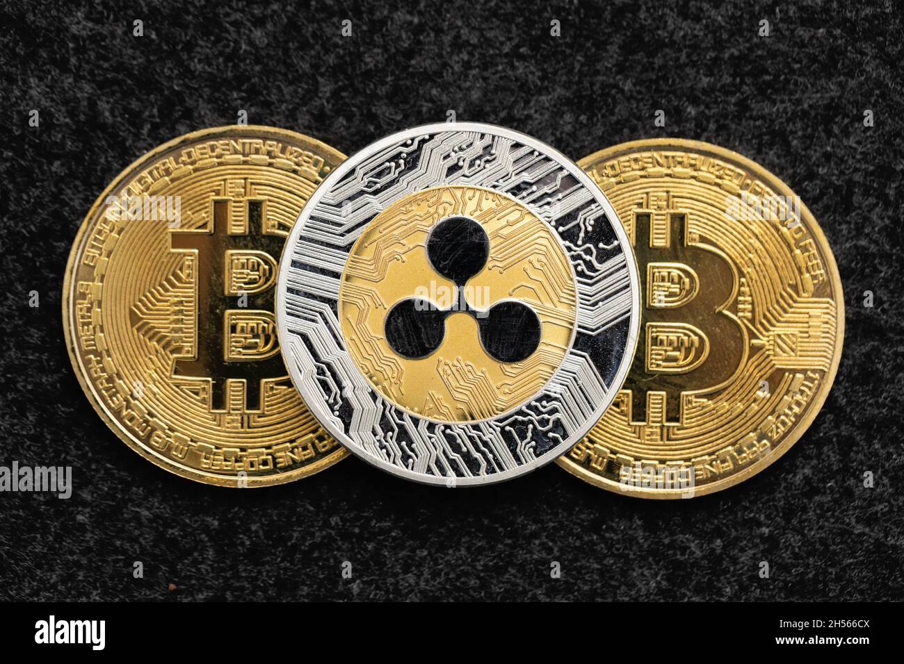 Ripple cryptocurrency coin laying on top of two bitcoin Stock Photo
