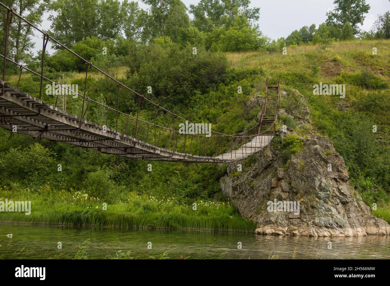 Old wooden suspension bridge over a small river Stock Photo - Alamy