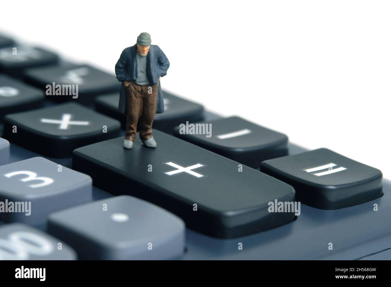 Poor man with no money left standing above calculator. Miniature tiny people toys photography. isolated on white background. Stock Photo