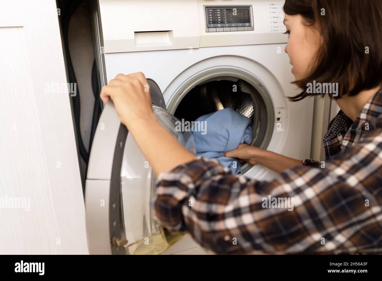 Woman puts bright clothes into a washing machine Stock Photo - Alamy
