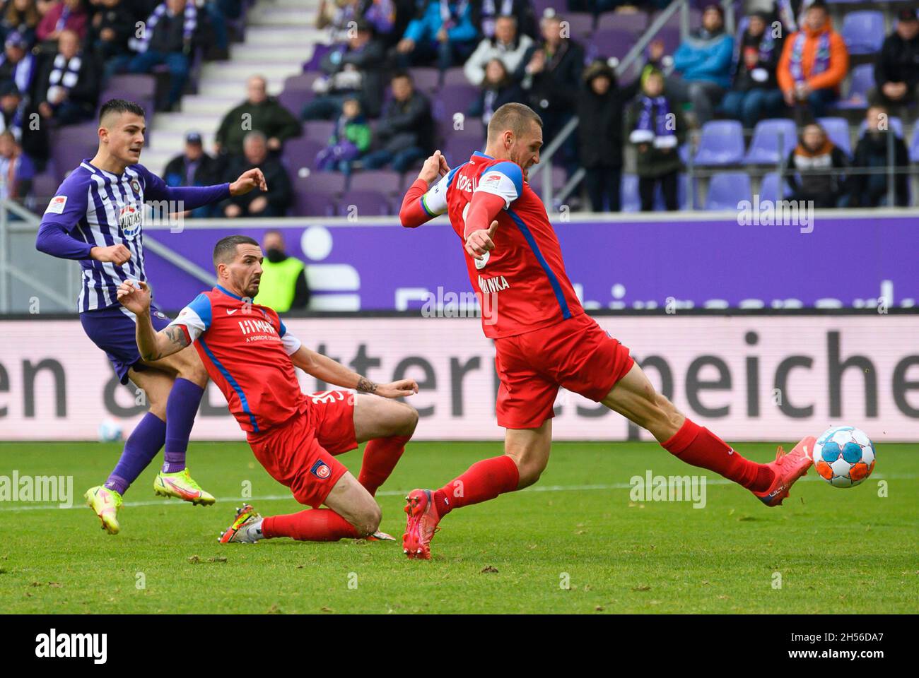07 November 2021, Saxony, Aue: Football: 2. Bundesliga, Erzgebirge Aue - 1. FC Heidenheim, Matchday 13, Erzgebirgsstadion. Aue's Antonio Jonjic (l) scores against Heidenheim's Norman Theuerkauf (m) and Patrick Mainka to make it 2:0. Photo: Robert Michael/dpa-Zentralbild/dpa - IMPORTANT NOTE: In accordance with the regulations of the DFL Deutsche Fußball Liga and/or the DFB Deutscher Fußball-Bund, it is prohibited to use or have used photographs taken in the stadium and/or of the match in the form of sequence pictures and/or video-like photo series. Stock Photo