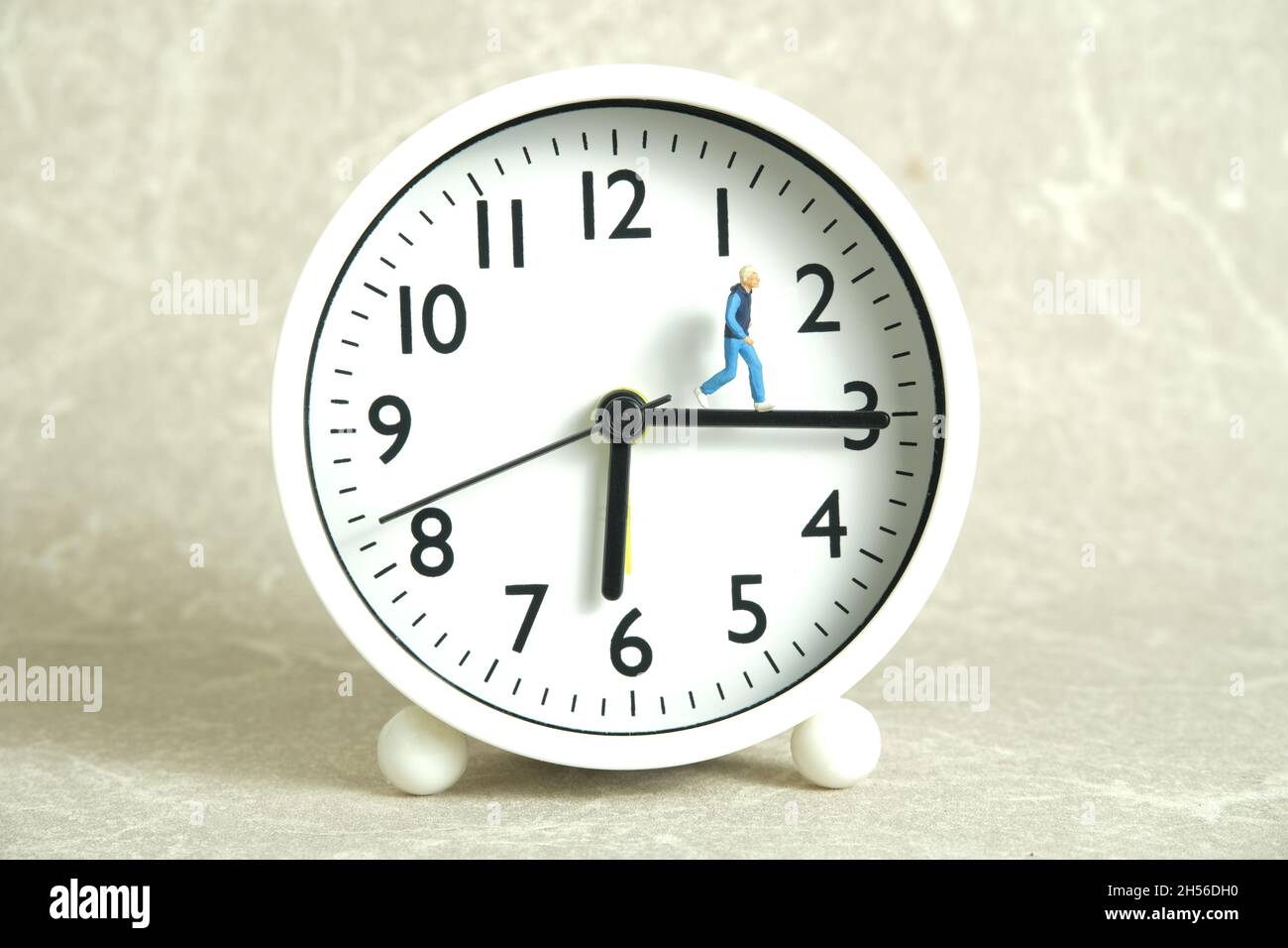 Miniature people toy figure photography. Running daily routine concept. A young men runner jogging above clock, isolated on white background. Image ph Stock Photo