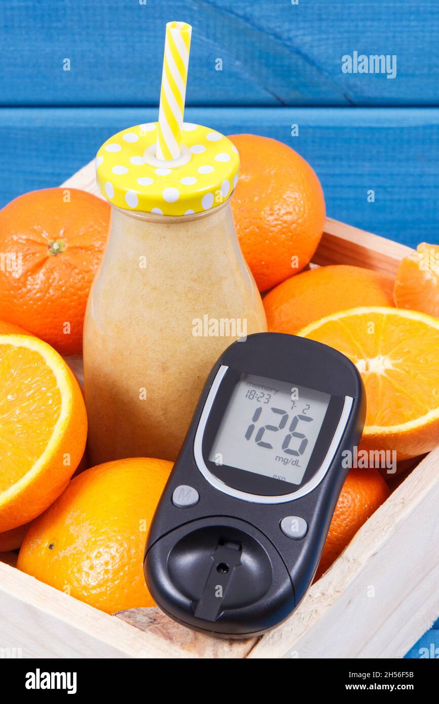 Glucose meter for checking sugar level and healthy coctail or juice from citrus fruits. Concept