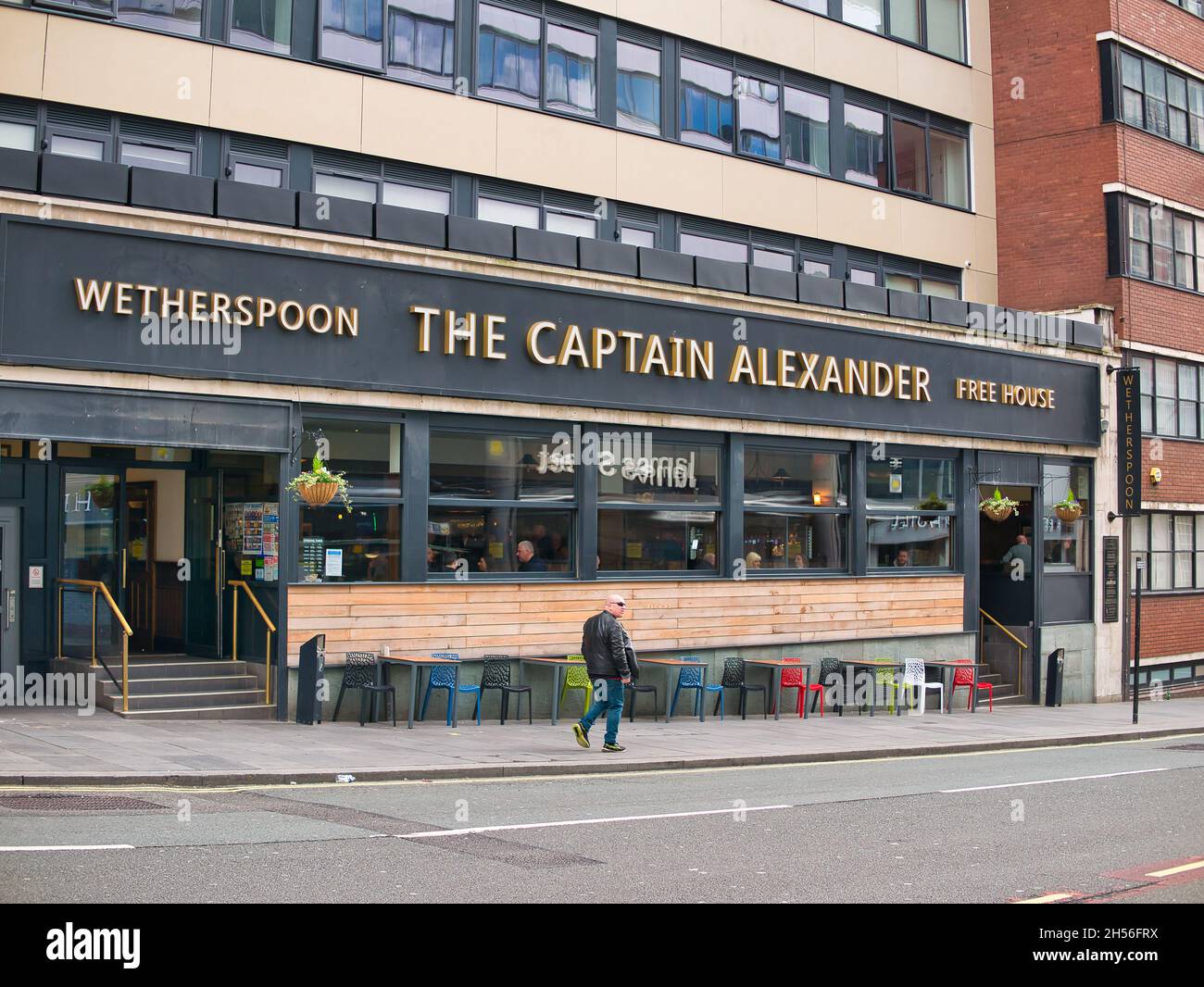 The Captain Alexander in James Street, Liverpool. A JD Wetherspoon public house. A single male passes on the pavement, while customers are visible thr Stock Photo