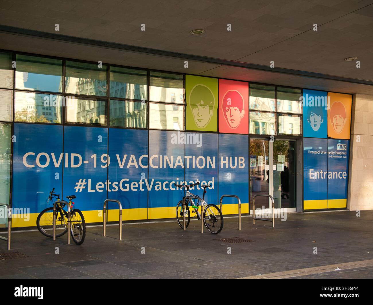 With  cycle lockup, the Covid-19 Vaccination Hub at the Pier Head, Liverpool in the north west of the UK. Images of The Beatles appear. Stock Photo