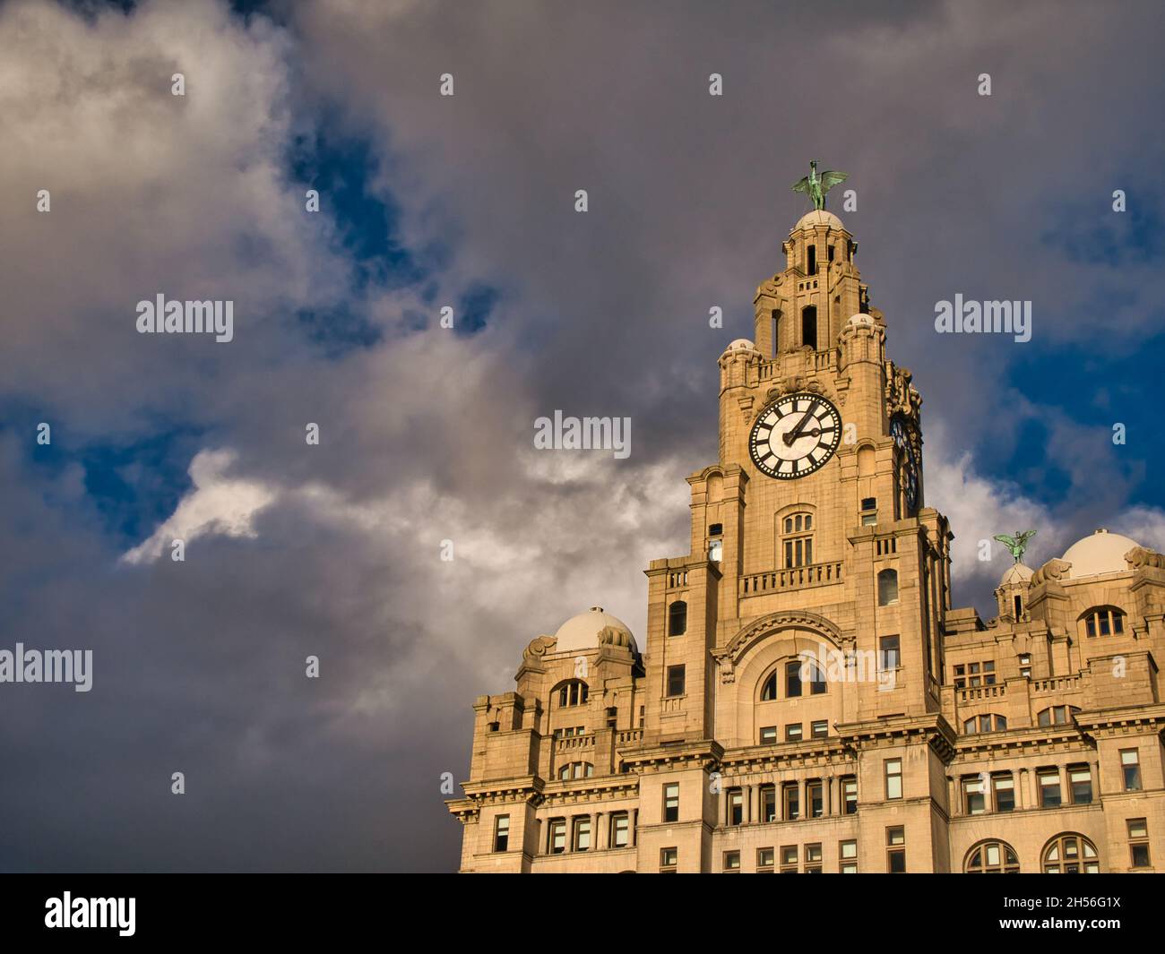 The clock tower and upper frontage of the Royal Liver Building in Liverpool, UK. Taken on a sunny day with threatening grey clouds. Stock Photo