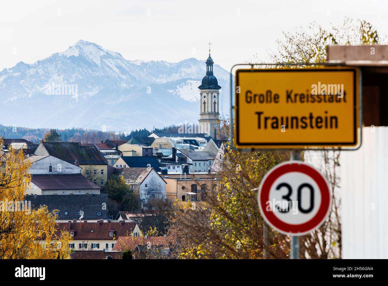 07 November 2021, Bavaria, Traunstein: The parish church of St. Oswald and the Bavarian foothills of the Alps can be seen behind the town sign 'Große Kreisstadt Traunstein'. The district of Traunstein is currently one of the Bavarian regions most affected by Corona. Photo: Matthias Balk/dpa Stock Photo