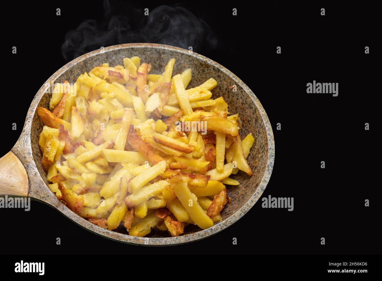 Delicious crispy golden hot fried potato wedges on an old metal frying pan close-up. Steaming freshly cooked homemade fried potatoes in frying pan iso Stock Photo