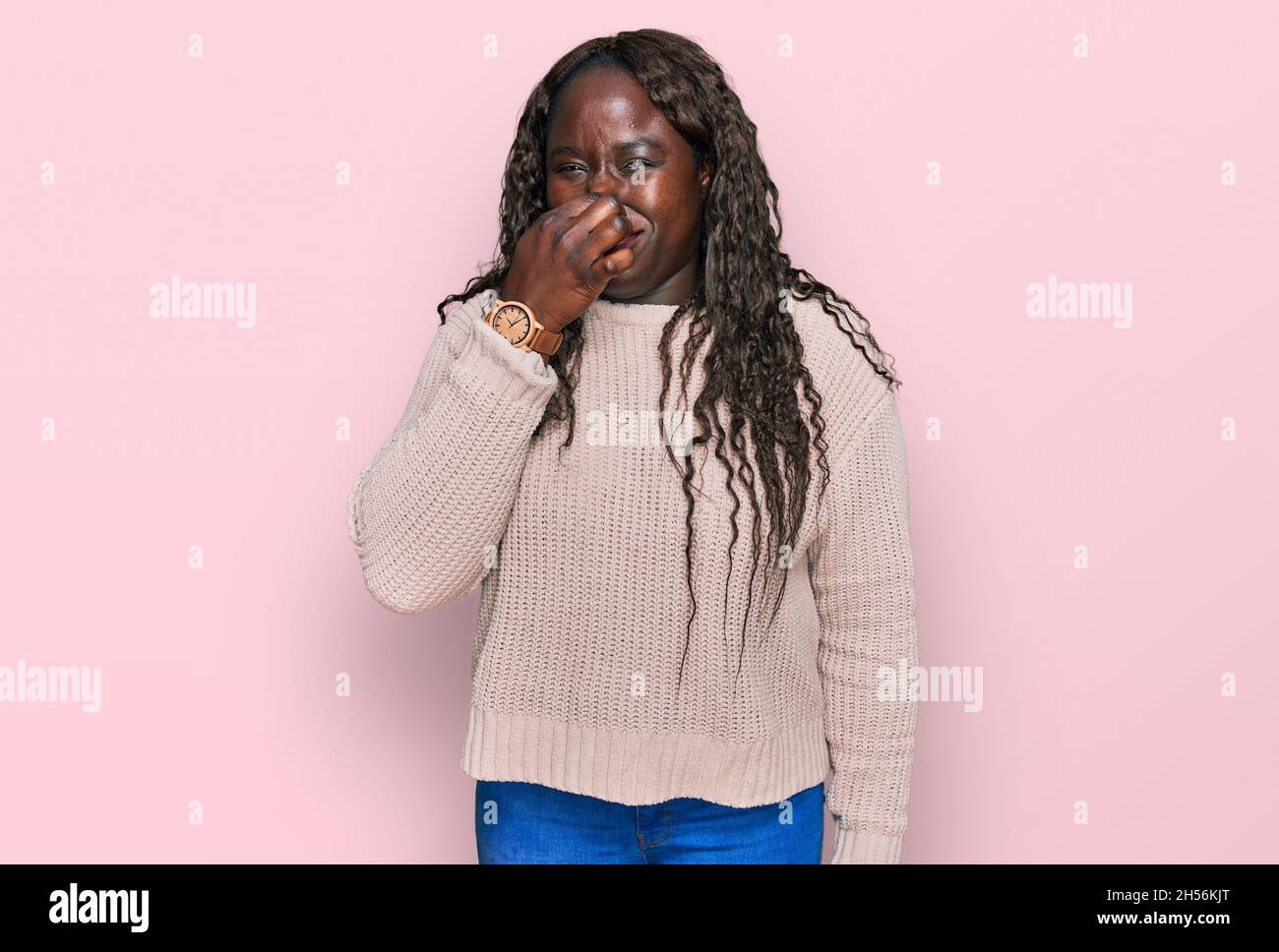 Young african woman wearing wool winter sweater smelling something