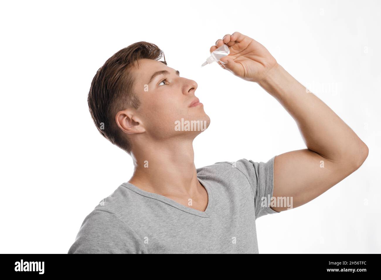 Concentrated millennial caucasian attractive guy dripping drops in eyes, suffering from dryness and pain Stock Photo