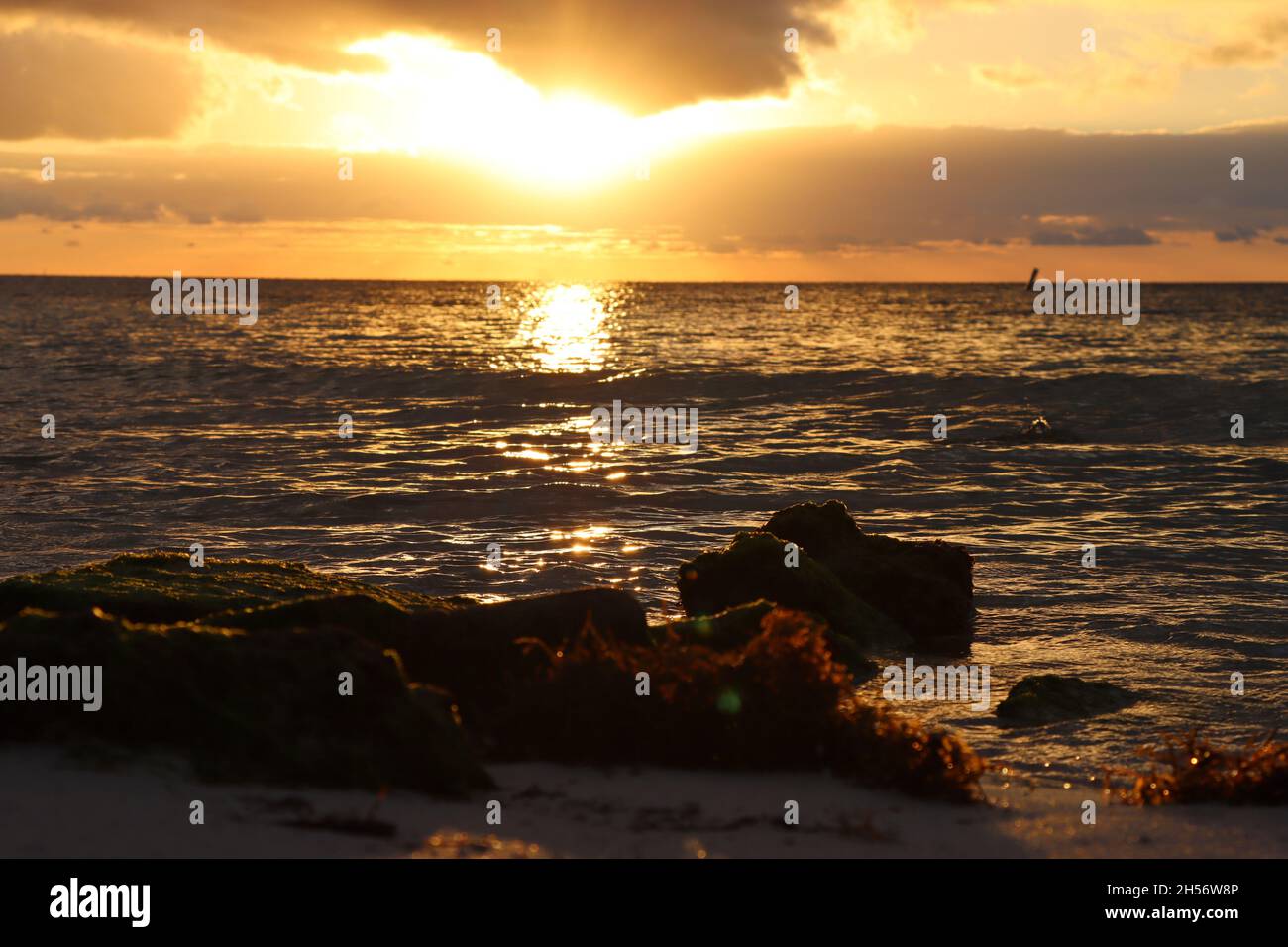 Stunning sunrise viewed from tropical rocky beach Stock Photo