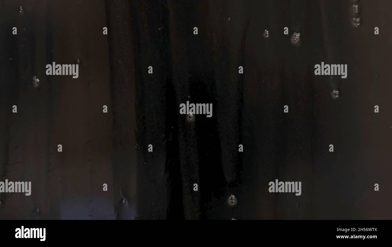 Closeup of drops running down dark glass. Concept. Rain drops slowly