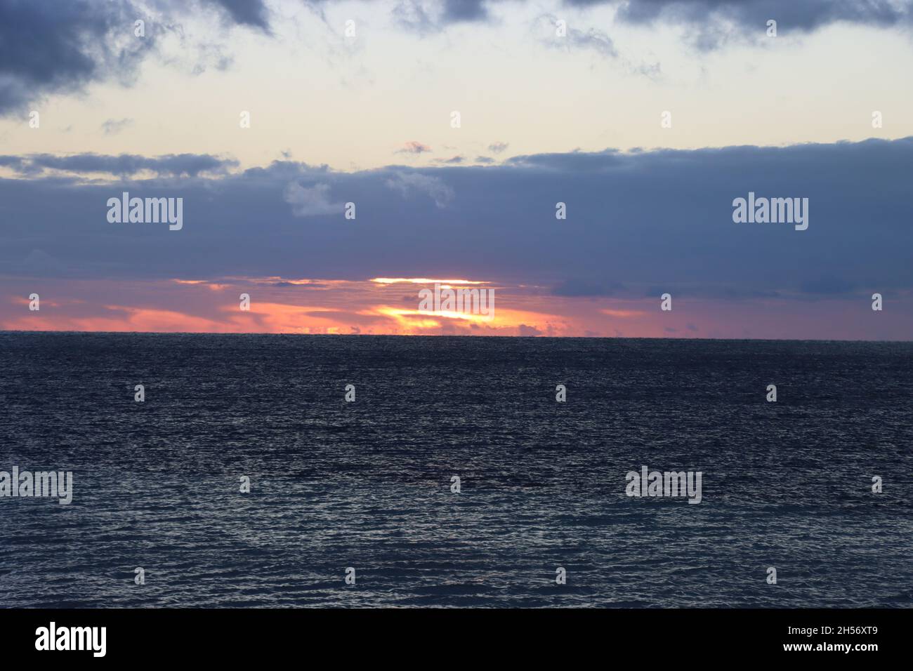 Stunning Fiery Sunrise with dark clouds over the ocean Stock Photo - Alamy