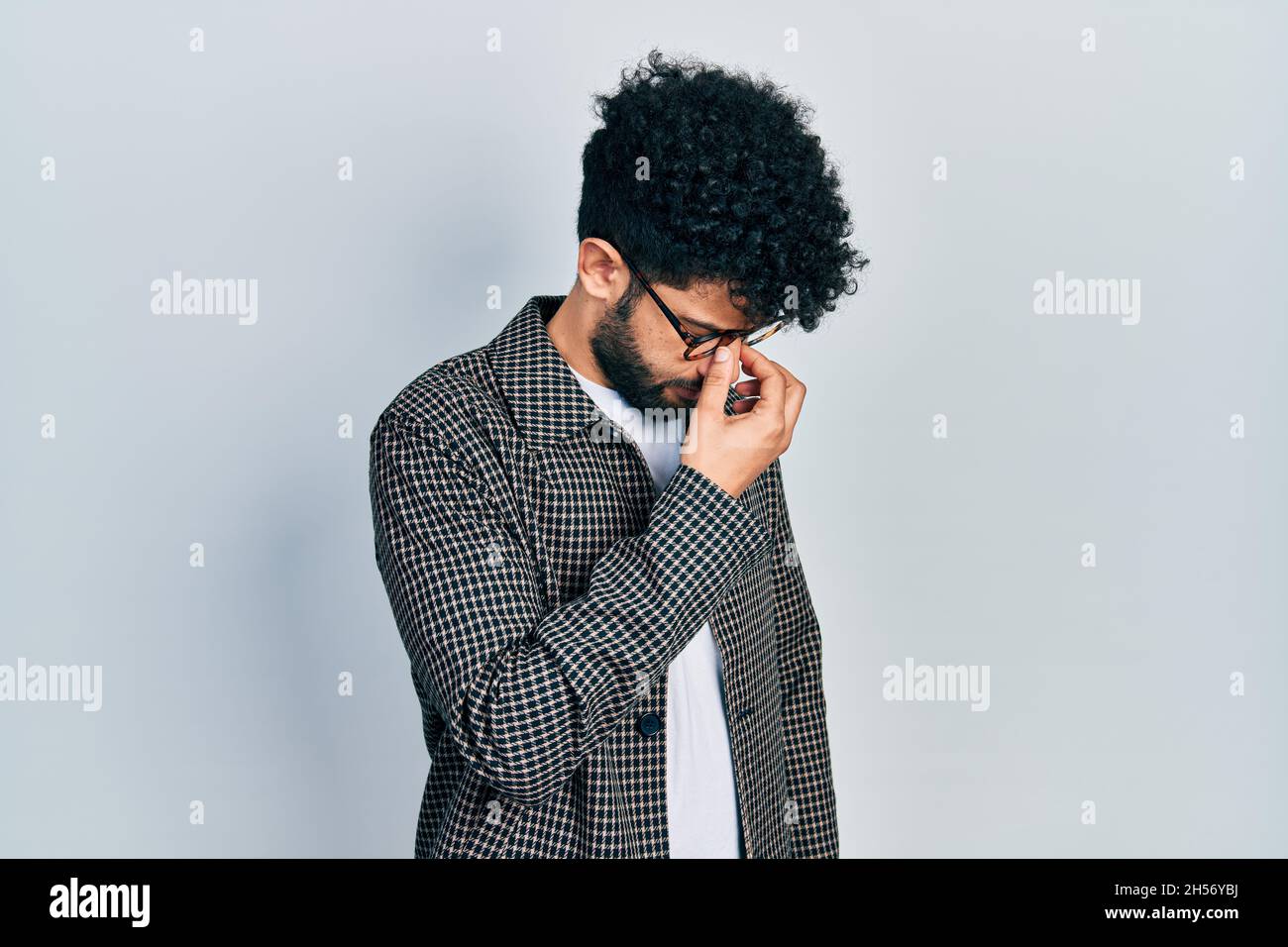 Young arab man with beard wearing glasses tired rubbing nose and eyes ...