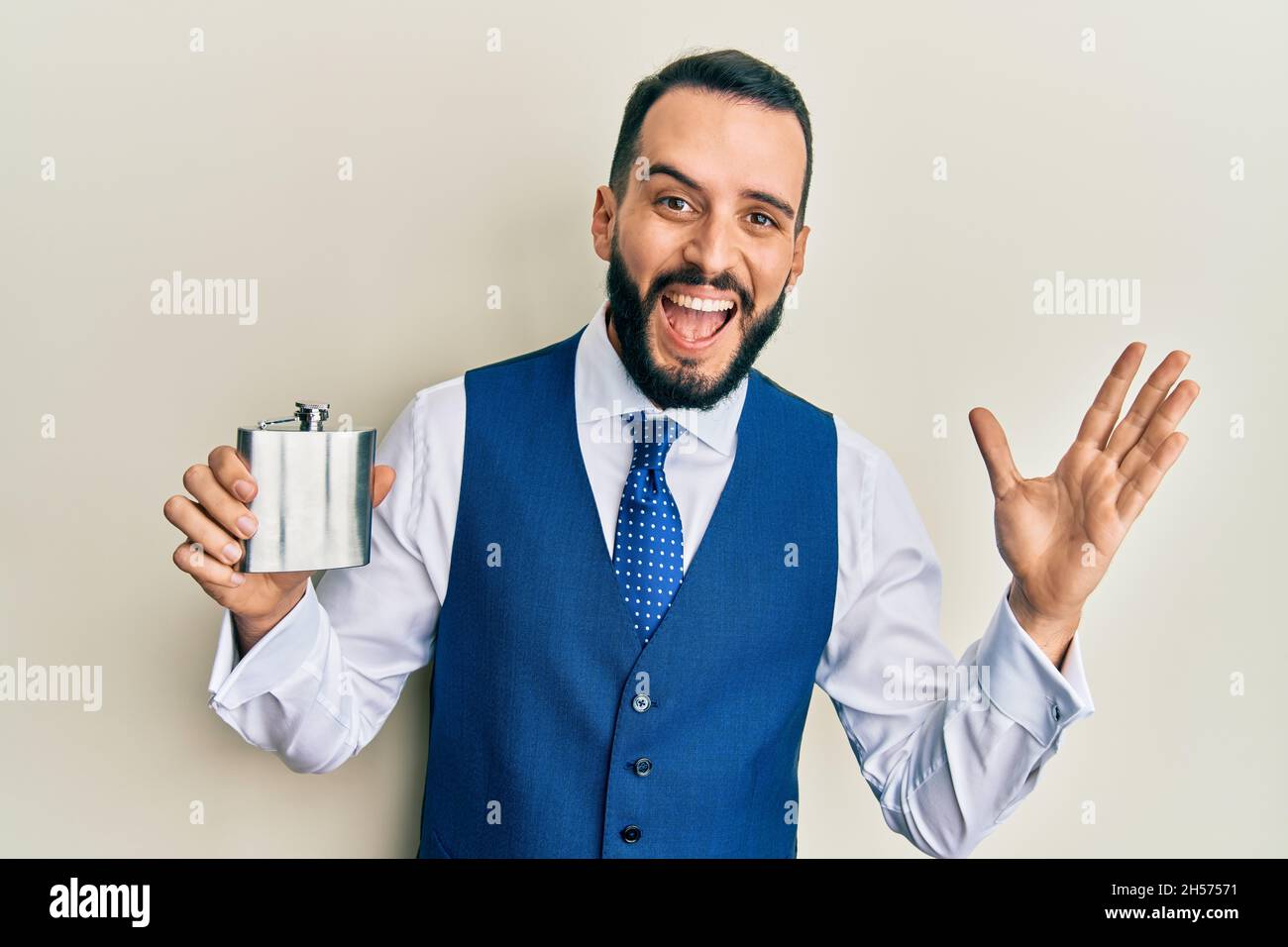 Young man with beard drinking whiskey from flask celebrating victory ...