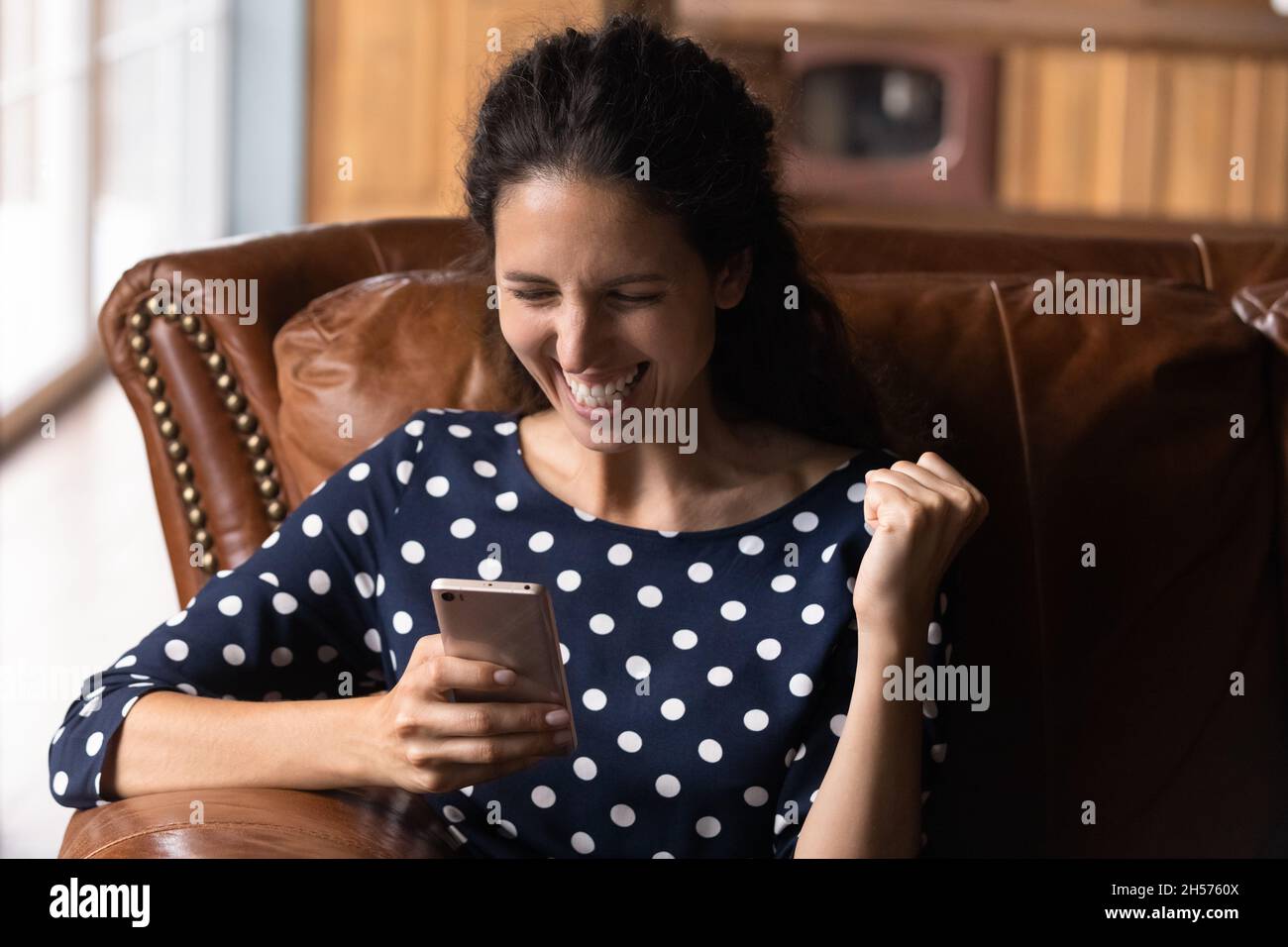 Excited hispanic female receive phone message of loan bank approval Stock Photo