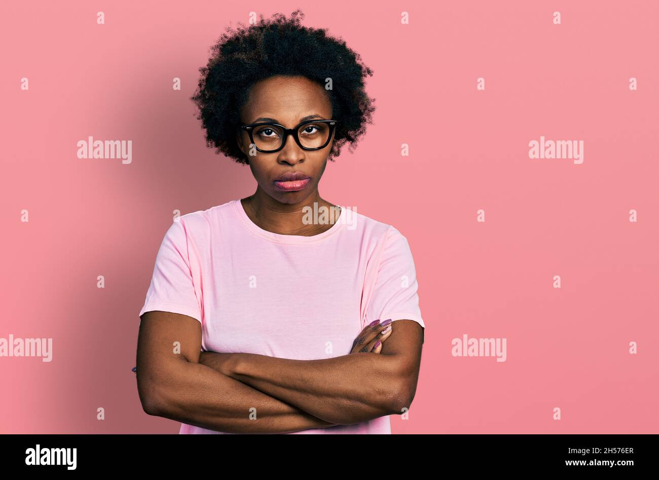 African american woman with afro hair wearing casual clothes and glasses skeptic and nervous, disapproving expression on face with crossed arms. negat Stock Photo