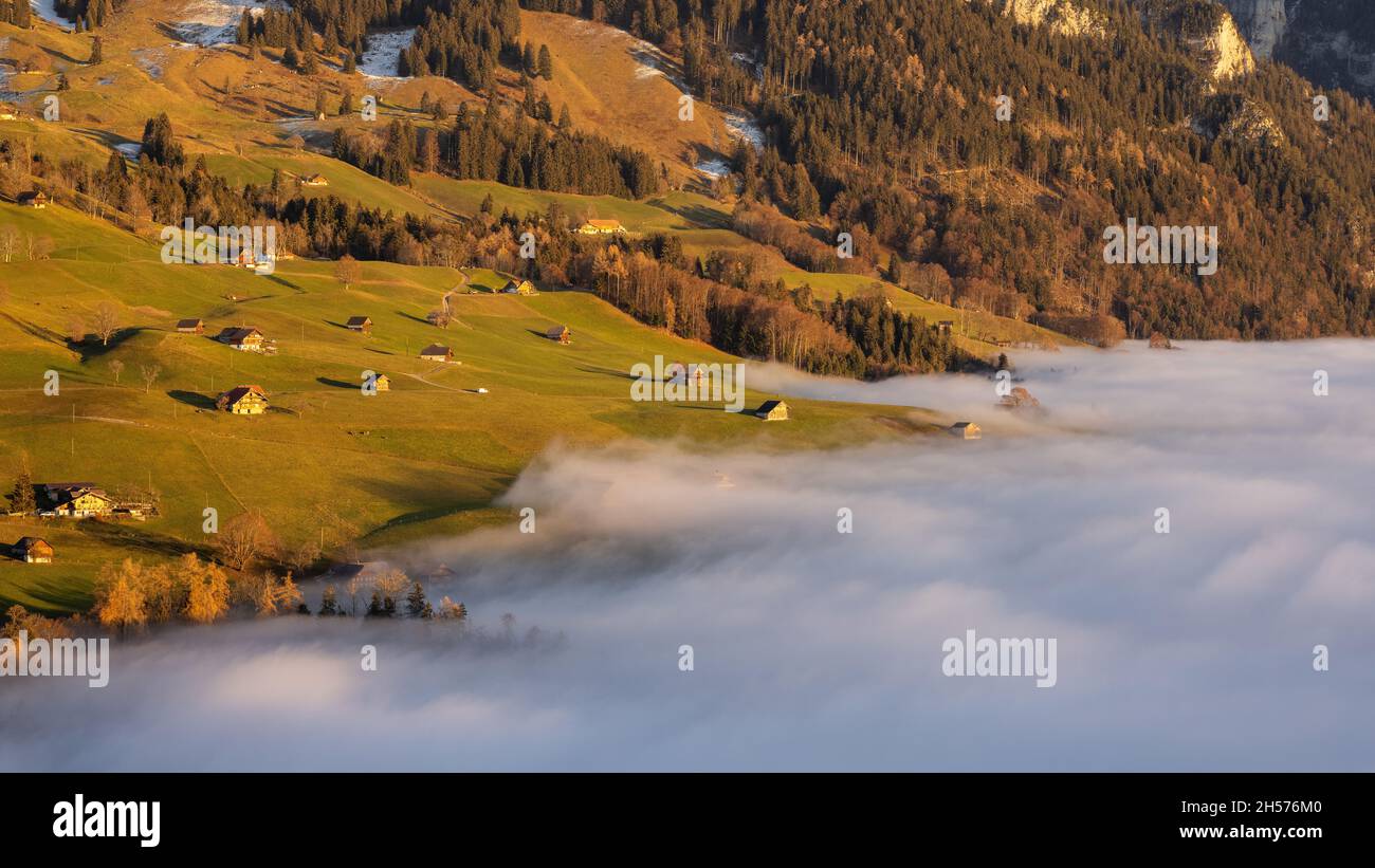 An aerial view of fog reaching the top of a mountain in Schwanden Stock Photo