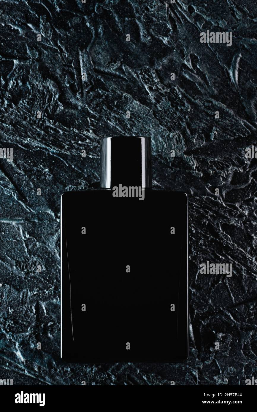 Silhouette of a black bottle of eau de toilette for men on a dark background. Advertising photo of perfumes. Dark style. Layout. Stock Photo