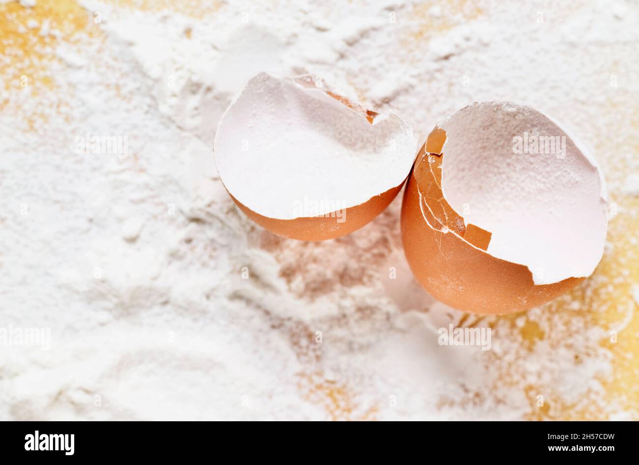 Broken eggshell with flour on yellow background Stock Photo