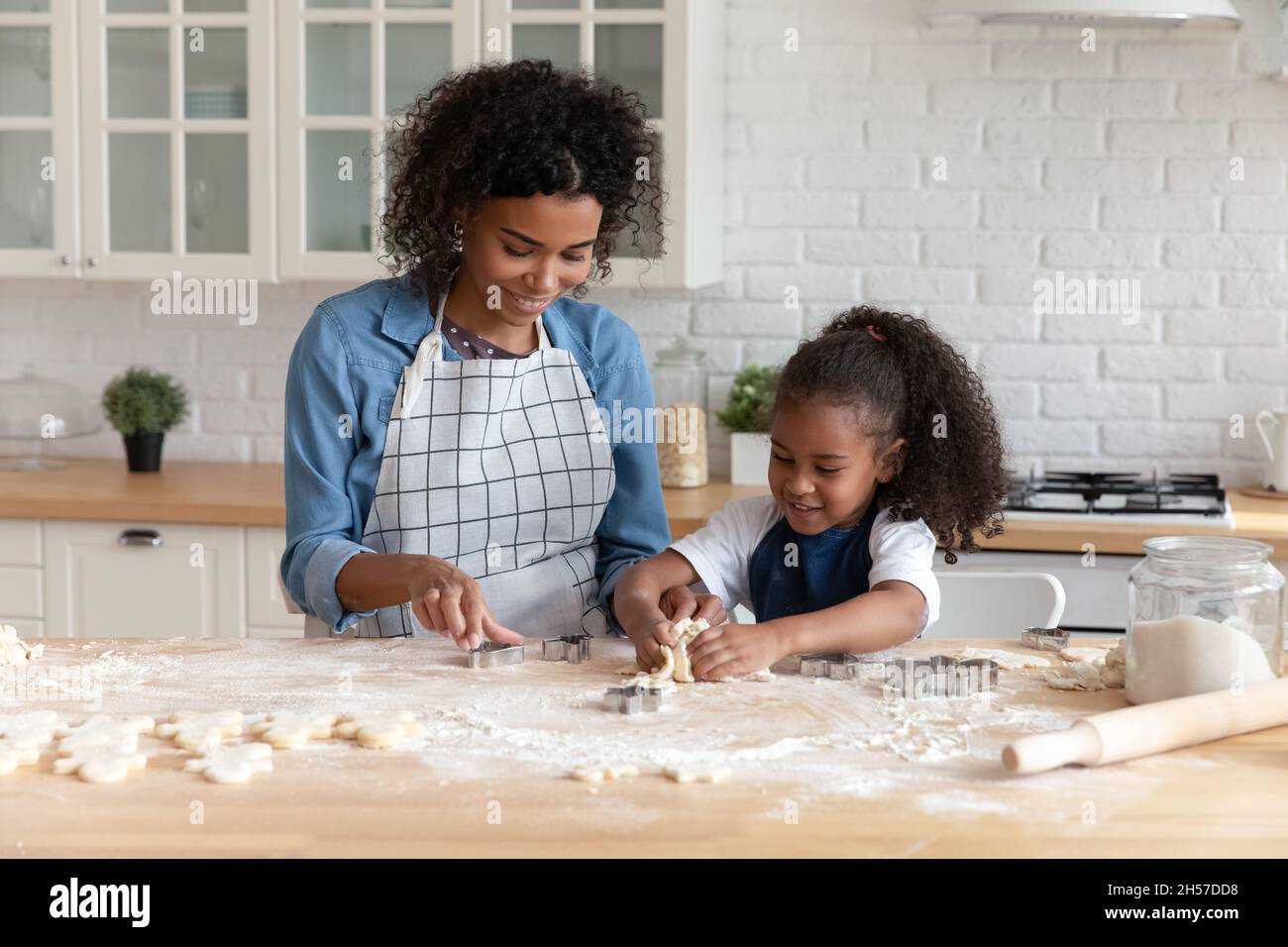 Happy African American mom helping cute daughter to bake biscuit Stock Photo Alamy