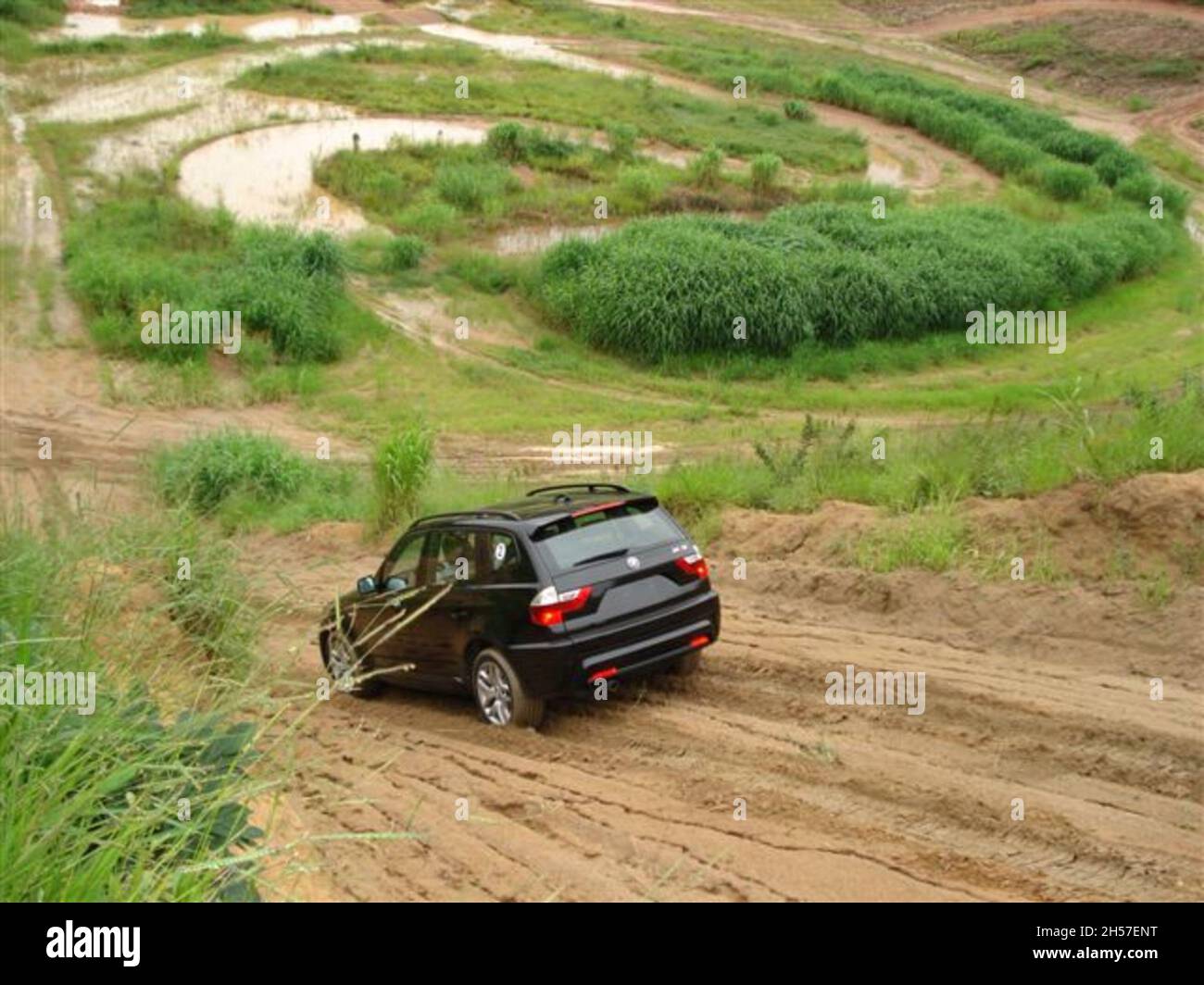 BMW X3 (E83): View from the rear of the car, driving down a muddy hill, black. First generation, produced from 2003 to 2010. São Paulo - Brazil Stock Photo