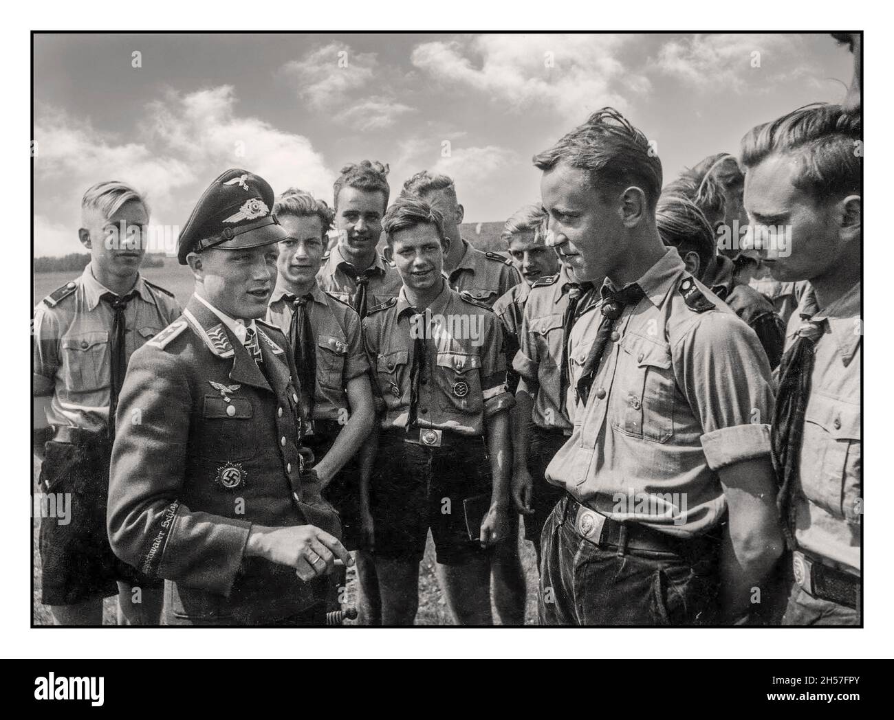 Nazi Propaganda Image 1940s Ritterkreuzträger (Knight's Cross recipient) Oberfeldwebel Wilhelm 'Willi' Freuwörth from Jagdgeschwader 52 (JG 52) shares his experiences with the Hitler Youth from the air section of the Hitlerjugend in Rossitten, East Prussia, 16 July 1944 He received the Ritterkreuz des Eisernen Kreuzes on 5 January 1943 as Feldwebel and Flugzeugführer in 2.Staffel / I.Gruppe / Jagdgeschwader 52 after 53 air victories (his total is 58). Stock Photo