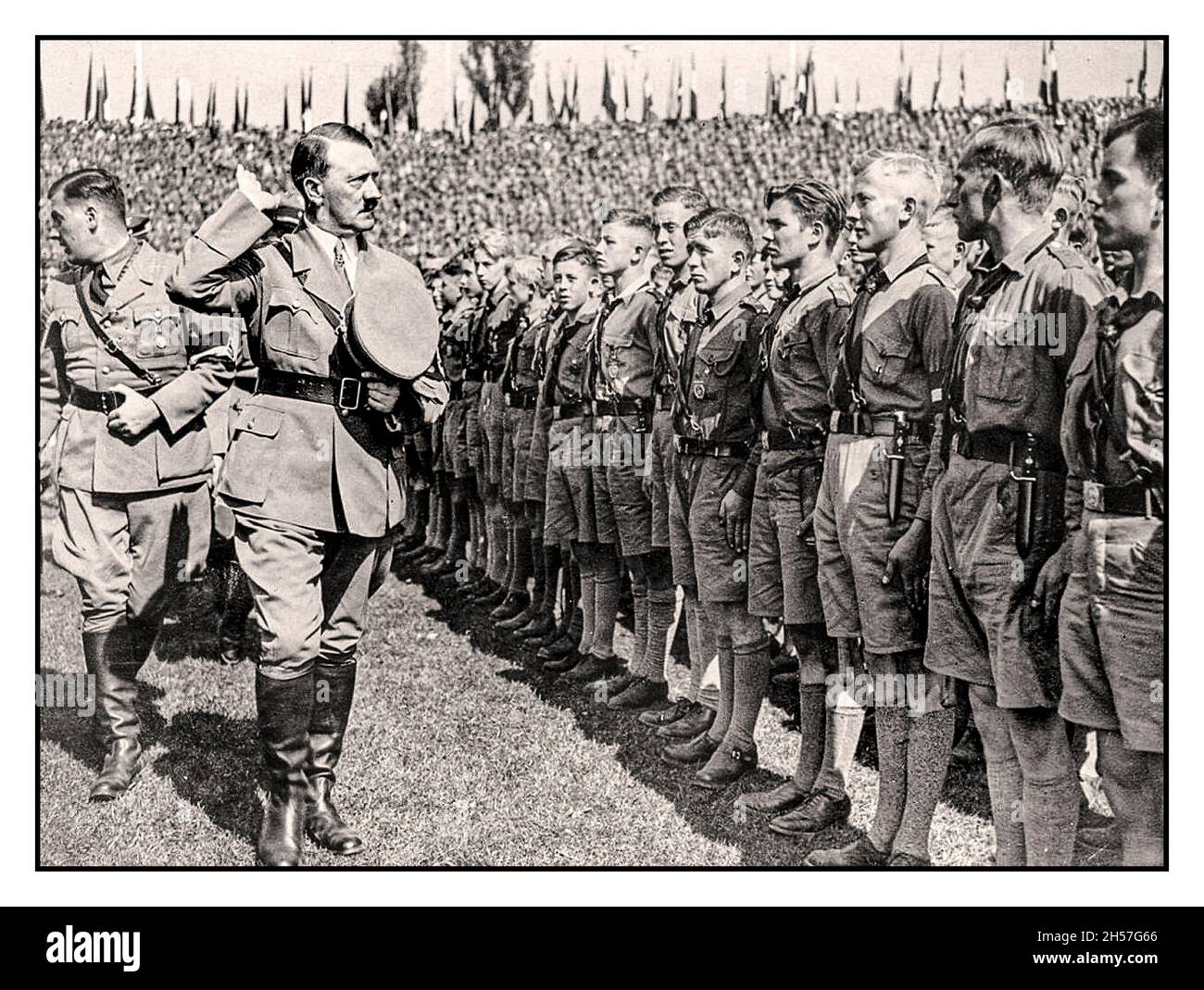 ADOLF HITLER  salutes a uniformed parade of Hitler Youth 'Hitlerjugend' wearing swastika armbands at a 1930s 'Nuremberg Rally in Nuremberg Nazi Germany - Stock Photo
