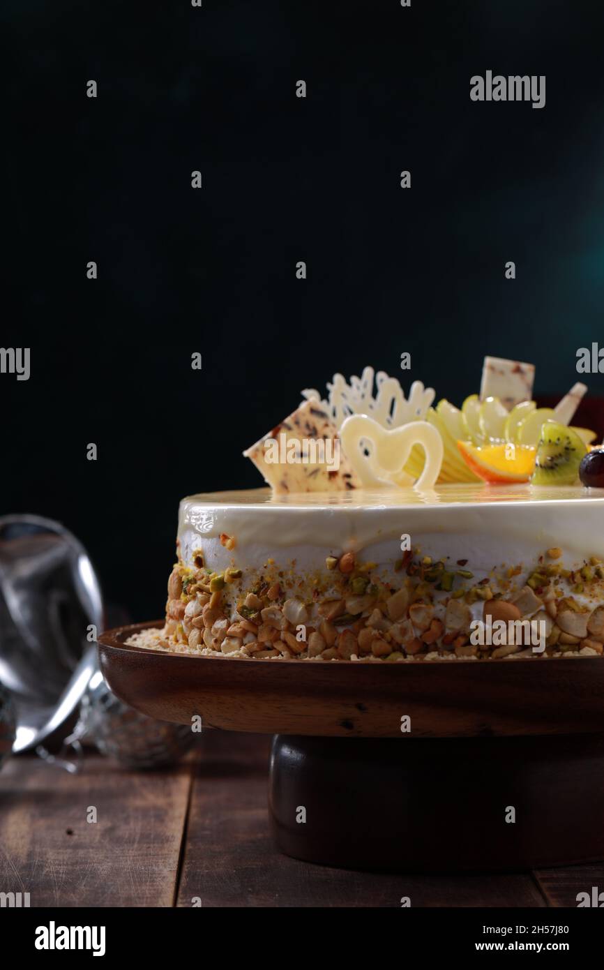 White Chocolate cake arranged on a rustic wooden background with gifts placed nearby. Stock Photo