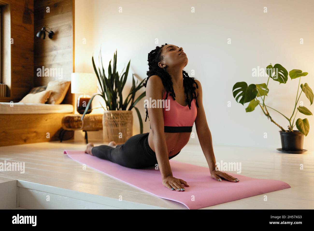 Time for yoga. Attractive and healthy young black woman doing exercises ...