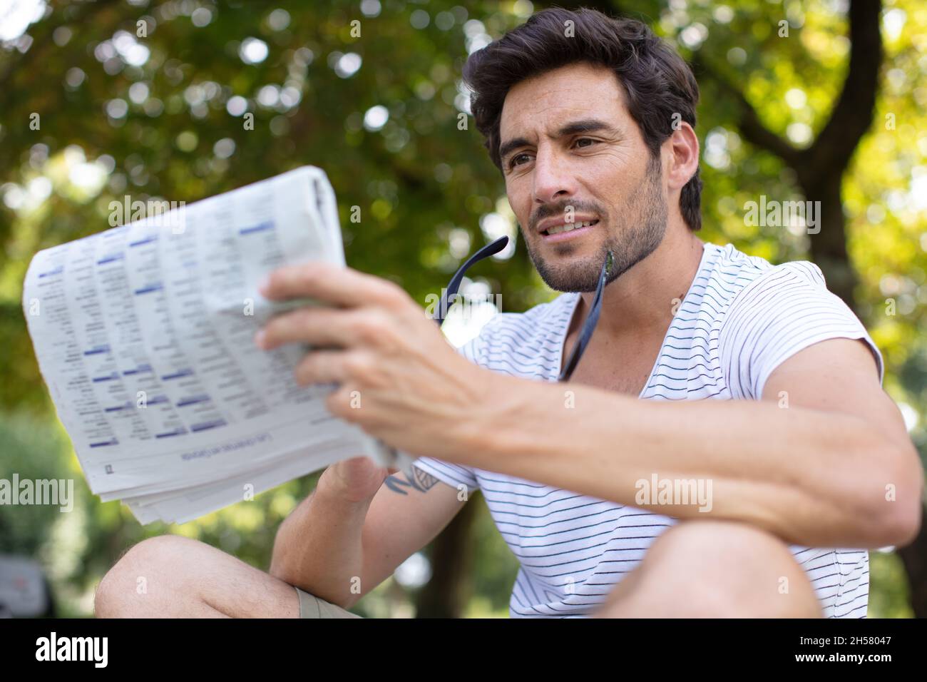 bearded young man reading newspaper on the bench Stock Photo - Alamy